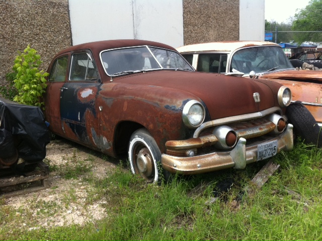 Rusty early 50s Ford in East Austin yard, 1